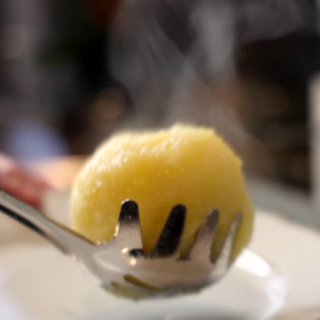 Fertiger dampfender Kloß, mit einer Kelle aus dem Wasser geschöpft. Kartoffelklöße und Semmelknödel sind Klassiker - nicht nur im Winter. Fertige Knödel enthalten teils schädliche Zusätze. Ist Kloßteig aus dem Kühlregal besser? Tipps und Rezepte zum Knödel selbermachen.