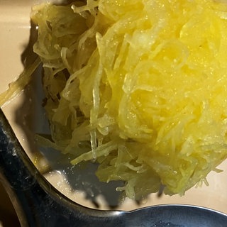 Zu sehen ist ein grüner Kloß aus rohen Kartoffeln, der auf einer Schöpfkelle liegt.