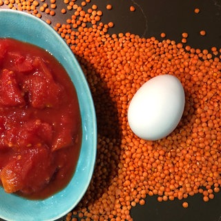 Dosentomaten in einer Schale, ein Ei und rote Linsen