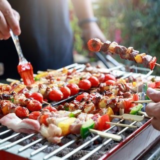Männer am Grill marineiren Grillspieße