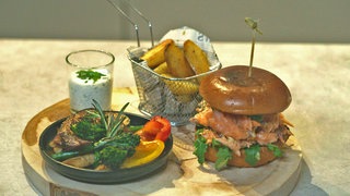 Flammlachsburger mit Grillgemüse und knusprigen Kartoffel-Wedges auf der Feuerplatte (Plancha)