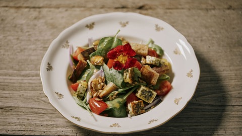 Sommersalat mit Ziegenbratkäse und Croutons auf einem Teller