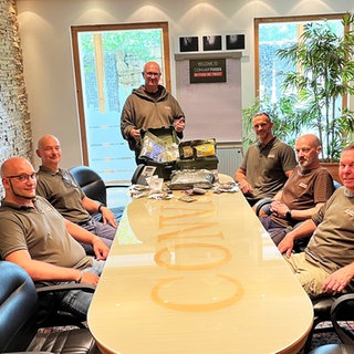 Das Team von Convar um einen Konferenztisch mit Produkten