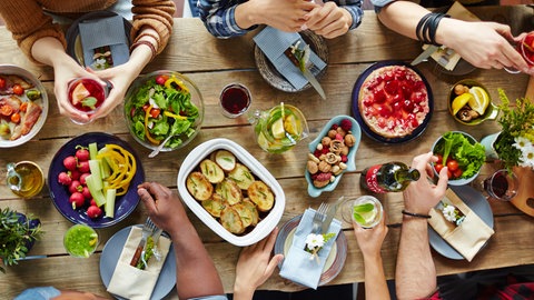 Ein gedeckter Tisch von oben, an dem verschiedene Menschen sitzen
