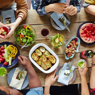Ein gedeckter Tisch von oben, an dem verschiedene Menschen sitzen
