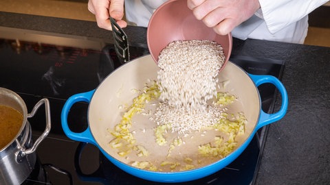 Bärlauch-Risotto kochen: Risotto wird in einen blauen Topf geschüttet.
