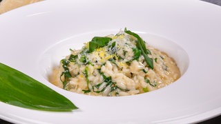 Das fertige Bärlauch-Risotto ist in einem weißen Teller angerichtet.