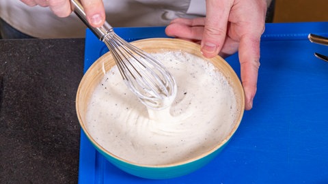Das Dressing für den Heringssalat wird in einer Schüssel angerührt. Danach wird der Salat laut Rezept mit Pellkartoffeln serviert.