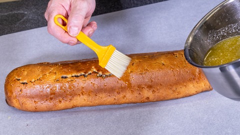 Nach dem Backen wird der Mohnstollen mit warmer Butter eingepinselt. Danach wird laut Rezept der Stollen in Zimtzucker gewälzt.