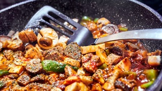Pilze eignen sich für viele Rezepte: Auf dem Bild werden verschiedene Pilze wie Kräuterseitlinge und Champignons mit Gemüse in der Pfanne gebraten.