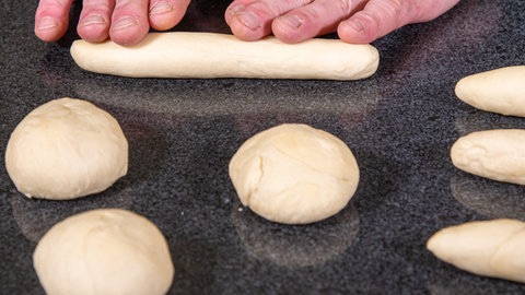 Teig wird erst in Kugeln und dann zu Stangen geformt.