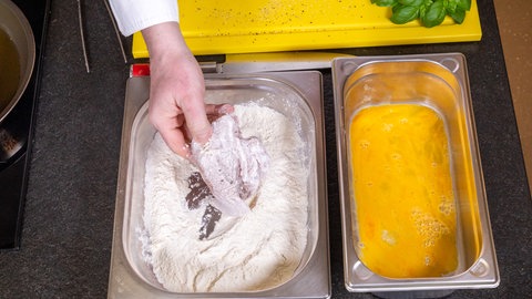 Die Geflügelbrust wird in Mehl und Ei für die Panade aus Parmesan vorbereitet.