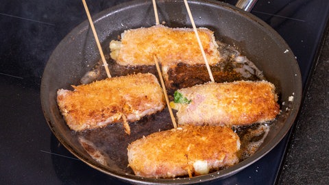 Panierte Spargelröllchen werden in Butterschmalz gebacken.