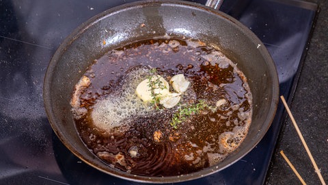 Zerlassene Butter in einer Pfanne mit Knoblauch und Thymian.
