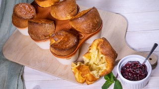 Pfitzauf nach original schwäbischem Rezept frisch aus dem Ofen auf einem Holzbrett mit Kompott serviert.