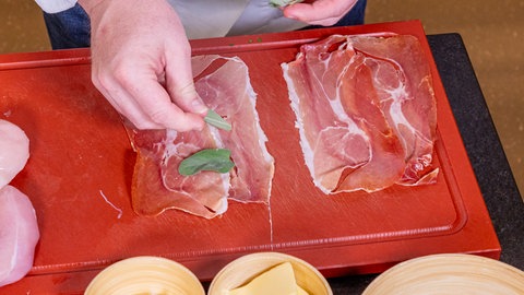 Rezept für Saltimbocca vom Hähnchen: Wie im Rezept beschrieben, wird für die Saltimbocca Schinken mit Salbeiblättern belegt. Dies wird dann um das Hähnchen gewickelt.