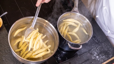 Auf einem Herd stehen 2 Töpfe mit Schupfnudeln für das Gericht Schupfnudeln mit Sauerkraut und Speck.
