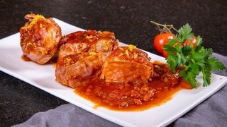 Schweinemedaillons im Speckmantel in fruchtiger Soße: Das Gericht ist schön angerichtet auf einem Teller.