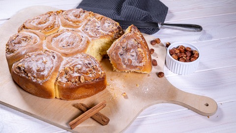 Fertig gebackene Zimtschnecken, die auf einem Brett angerichtet sind.