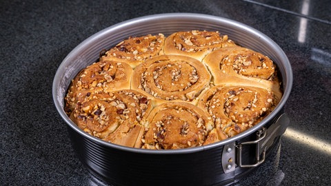 In einer Backform sind goldbraun gebackene Zimtschnecken.