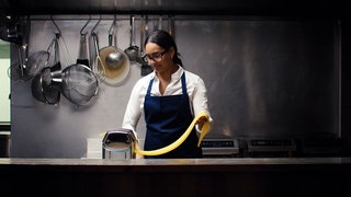 Die Ulmer Köchin Alina Meissner-Bebrout in der Küche. Sie bereitet Nudeln mit einer Nudelmaschine zu.