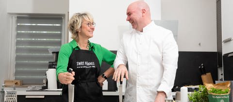 SWR1 Moderatorin Petra Klein und SWR1 Pfännle-Koch Eberhard Braun stehen in einer Küche und kochen zusammen.