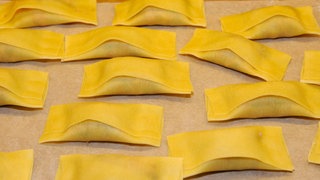 Maultaschenherstellung im schwäbischen Haushalt. Gefüllte Maultaschen liegen nebeneinenader auf einer Arbeitsfläche.