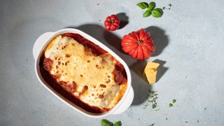 In einer weißen Auflaufform sind Cannelloni mit Merguez-Würsten als Auflauf angerichtet. 