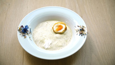 Kräutersuppe mit frittiertem Ei in einem Suppenteller