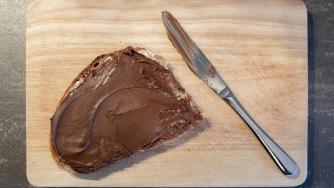 Nuss-Nougat-Creme dick auf eine Scheibe Brot geschmiert