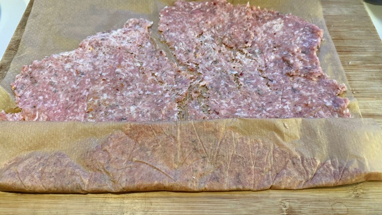 Fleischfladen mit Backpapier zu einem Päckchen zusammengeklappt.