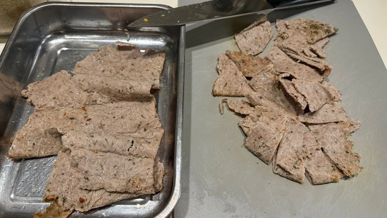 Hauchdünnes, gegartes Fleisch in Stücke zerteilt.