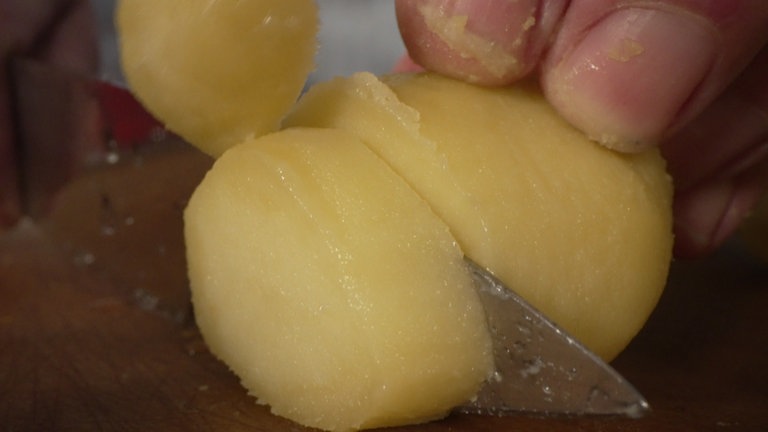 Damit die Kartoffelscheiben nicht aneinander kleben, empfiehlt es sich, das Messer zwischendurch unter Wasser zu halten.