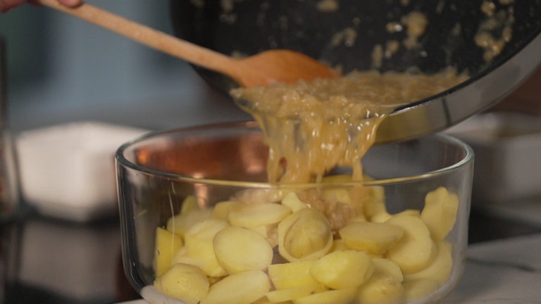 Die Marinade wird noch heiß über die Kartoffeln gegossen. So entsteht eine besonders cremige Konsistenz.