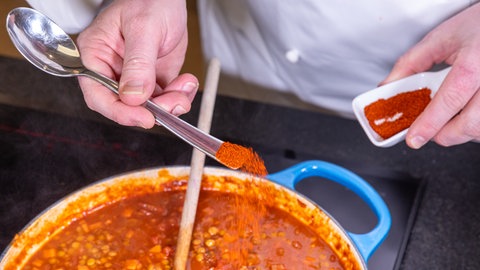 Nach dem Köcheln wird die vegetarische Bolognese mit Linsen kräftig abgeschmeckt – auch mit Paprikapulver. 