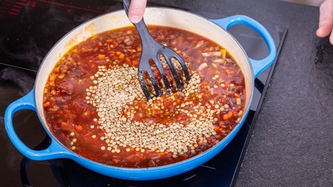 Sind auch die Tomaten und Kräuter in der Pfanne, sollten die vegetarische Bolognese mit Linsen 25 Minuten köcheln. 