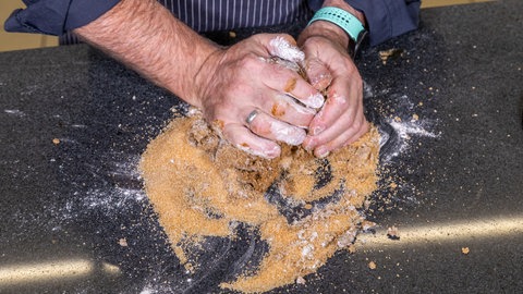 Teig für Printen wird auf einer Arbeitsfläche geknetet.