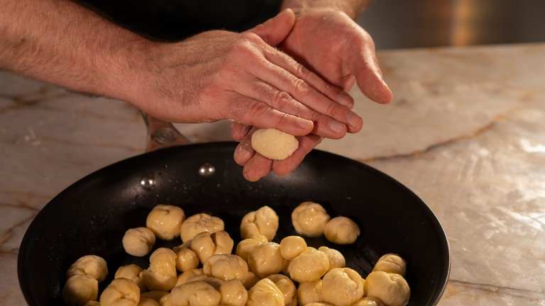 Den Teig in kleine Kugeln formen und in Butter wälzen. 