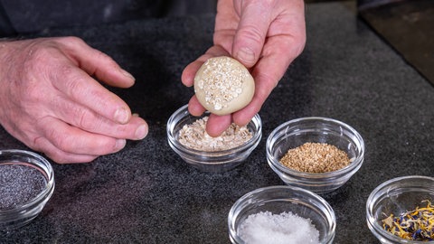 Die Brötchen werden mit Salz, Blüten, Mohn oder Sesam bestreut.