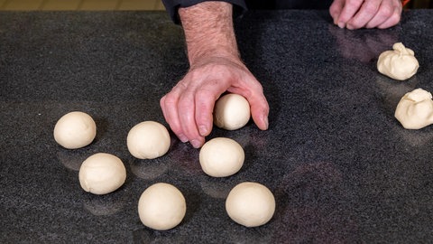 Der Teig wird zu kleinen Brötchen geformt.