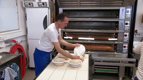 Michael Heiß backt Brot. Er steht vor einem Brotofen.
