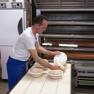 Michael Heiß backt Brot. Er steht vor einem Brotofen.