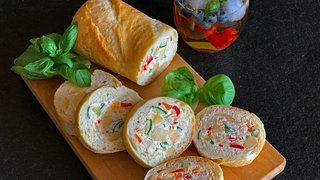 Gefülltes Baguette, sogenanntes Mosaikbrot, mit Essiggurken, Schinken und Käse.