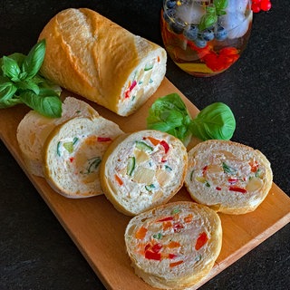 Gefülltes Baguette, sogenanntes Mosaikbrot, mit Essiggurken, Schinken und Käse.