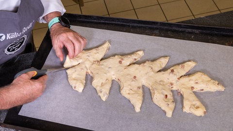 Der Teig für das Brot mit Speck und Zwiebeln wird vor dem Backen mit einer Schere in Form geschnitten.