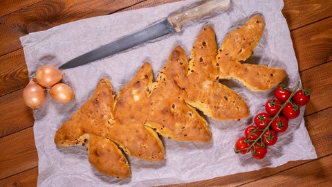 Das fertig gebackene Brot aus Dinkel mit Speck und Zwiebeln ist mit Cocktailtomaten angerichtet.