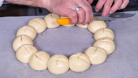 Das Laugengebäck für den Laugenkranz wird, wie im Rezept beschrieben, mit einem Messer vor dem Backen mit einem Messer eingeschnitten.