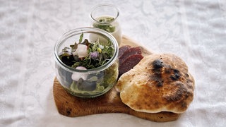 Salat mit Bisonsalami und Rancher-Brot auf einem Holzbrett 