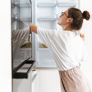 Frau legt etwas in Gefrierfach oder Kühlschrank