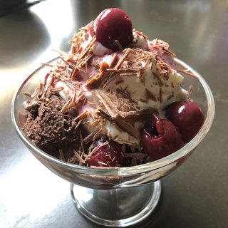 Eisbecher mit Schokoeis, Sauerkirschen, Schokoladenflakes und Sahne